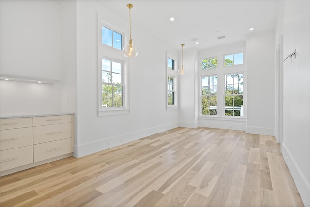 unfurnished living room with crown molding and light hardwood / wood-style flooring