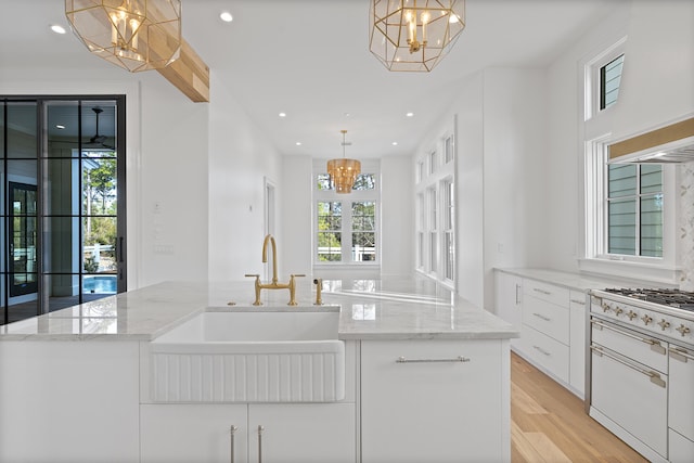 kitchen featuring white cabinetry, hanging light fixtures, an island with sink, and a chandelier