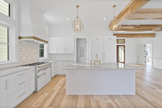 kitchen with high end white range oven, a kitchen island with sink, custom range hood, and white cabinets