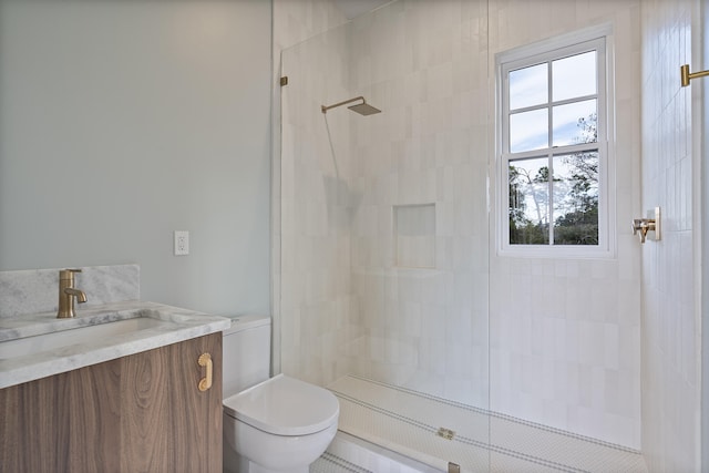 bathroom featuring vanity, toilet, and a tile shower