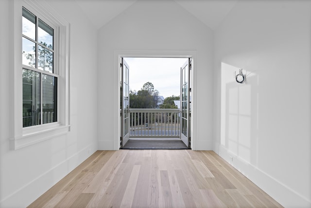 unfurnished room with a healthy amount of sunlight, vaulted ceiling, and light wood-type flooring