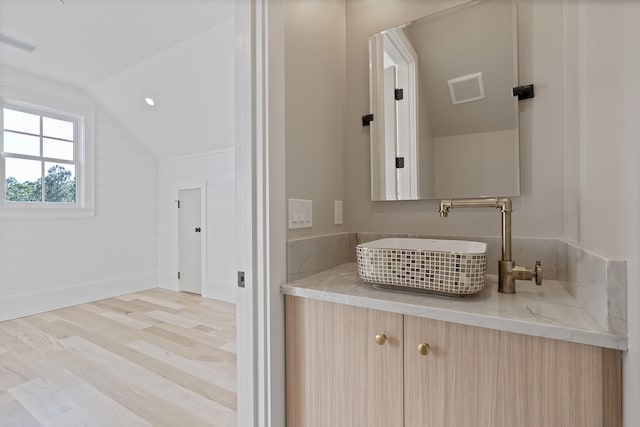 bathroom featuring hardwood / wood-style flooring, vaulted ceiling, and vanity