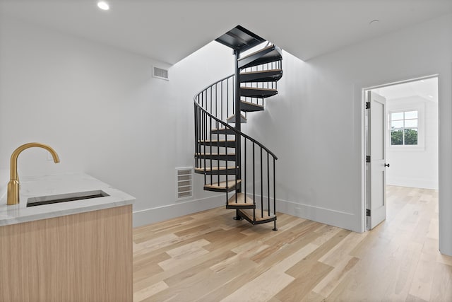 stairway with sink and hardwood / wood-style flooring