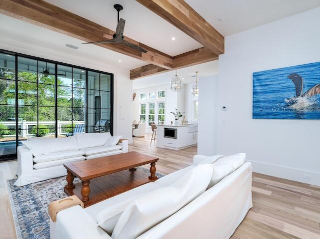 living room with beam ceiling, light wood finished floors, ceiling fan, and visible vents