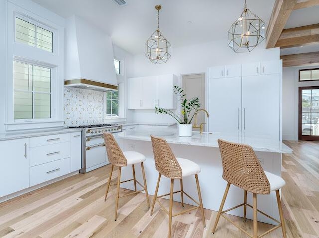 kitchen with decorative light fixtures, light wood-style flooring, double oven range, and custom range hood