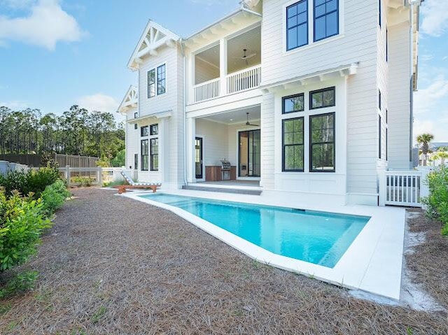 back of house with fence, a patio area, a fenced in pool, and a balcony