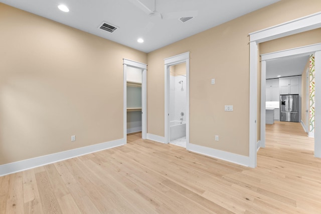 unfurnished bedroom featuring ensuite bathroom, ceiling fan, a spacious closet, stainless steel fridge with ice dispenser, and light hardwood / wood-style floors