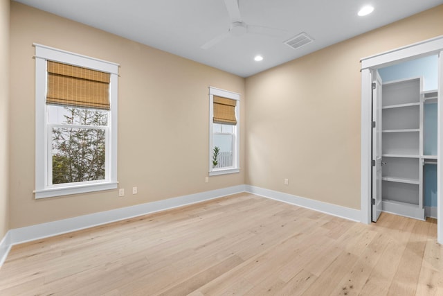 unfurnished bedroom featuring light wood-type flooring, a spacious closet, and ceiling fan