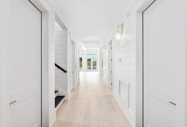 corridor with light hardwood / wood-style floors and wood walls