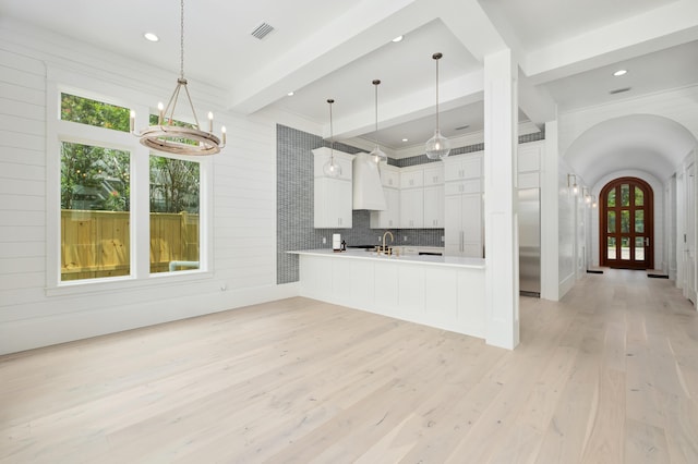 kitchen with kitchen peninsula, light hardwood / wood-style flooring, beamed ceiling, white cabinets, and hanging light fixtures