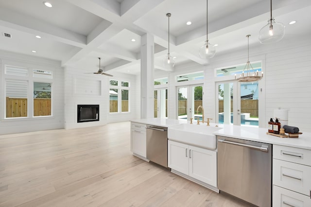 kitchen featuring white cabinets, dishwasher, a fireplace, and decorative light fixtures