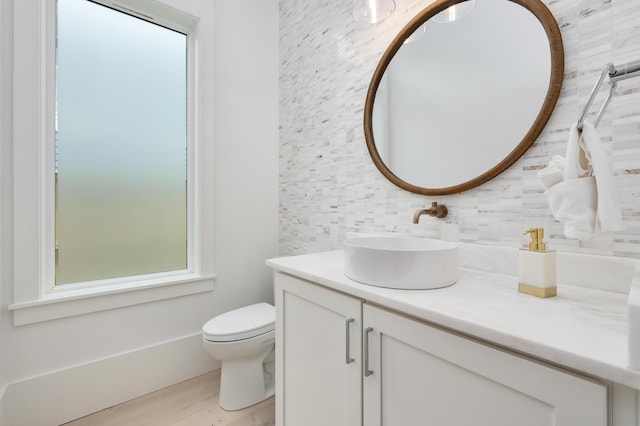 bathroom featuring vanity, toilet, wood-type flooring, and tasteful backsplash