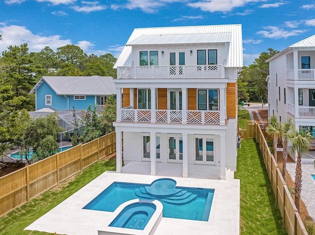 back of property featuring a lawn, a patio area, a balcony, and a pool with hot tub