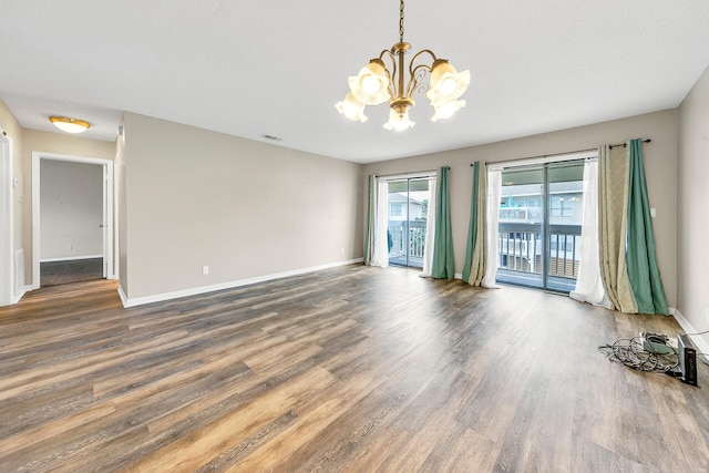 unfurnished room with wood-type flooring and a notable chandelier