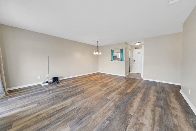 unfurnished living room with dark wood-type flooring and an inviting chandelier