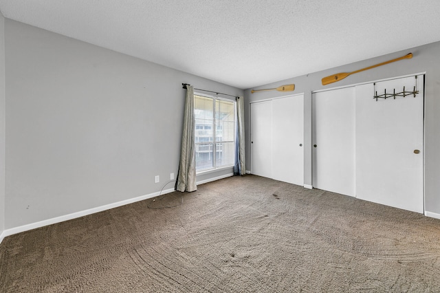 unfurnished bedroom with multiple closets, a textured ceiling, and carpet flooring