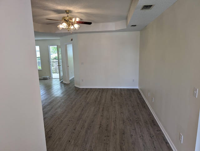 empty room with wood finished floors, ceiling fan, baseboards, and visible vents