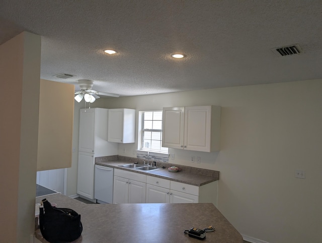kitchen with a sink, visible vents, white dishwasher, and a textured ceiling