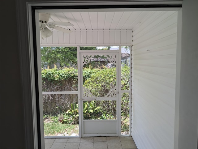 doorway with ceiling fan and tile patterned flooring