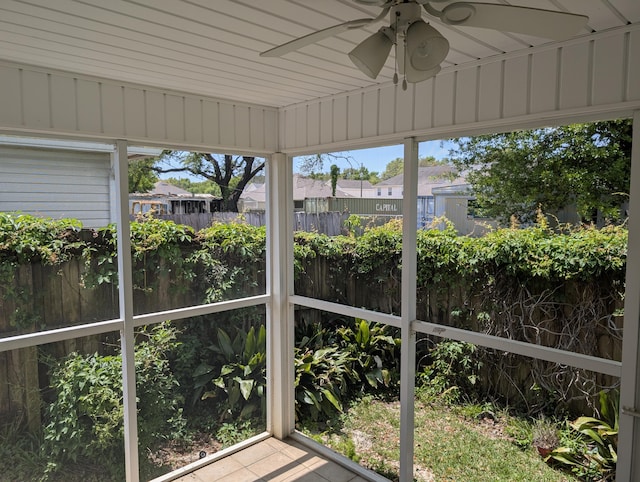 unfurnished sunroom with a ceiling fan and a residential view