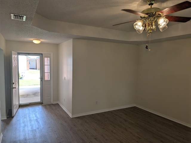 foyer featuring a textured ceiling, a ceiling fan, visible vents, baseboards, and dark wood-style floors
