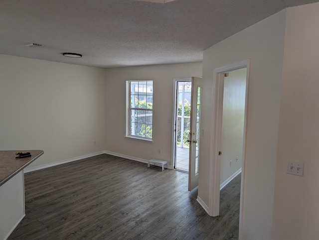 interior space featuring baseboards, a textured ceiling, and dark wood finished floors