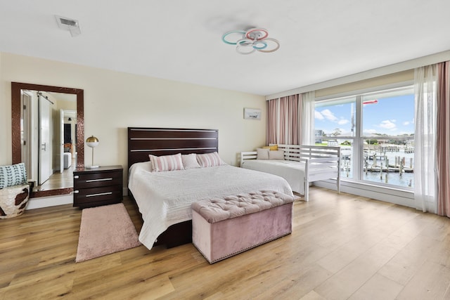 bedroom featuring a water view and light wood-type flooring