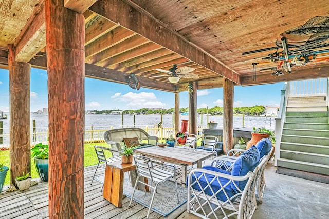 deck with outdoor lounge area, ceiling fan, and a water view