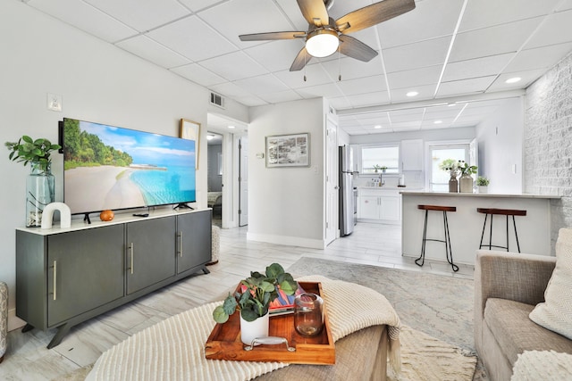 living room with a paneled ceiling and ceiling fan