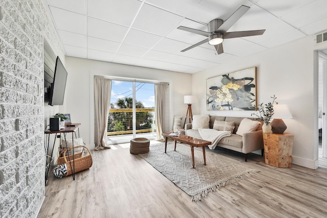 living room featuring ceiling fan, a drop ceiling, and light hardwood / wood-style flooring