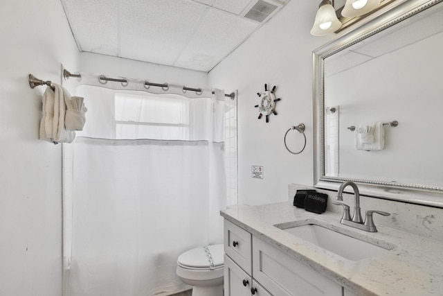 full bathroom featuring a paneled ceiling, vanity, toilet, and shower / bathtub combination with curtain