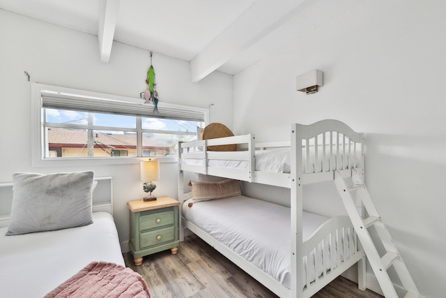 bedroom with beam ceiling and hardwood / wood-style flooring