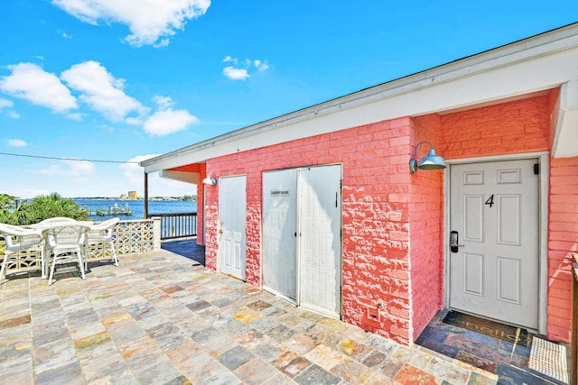 view of exterior entry featuring a patio area and a water view