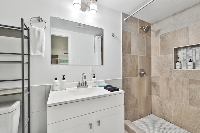 bathroom featuring toilet, vanity, and tiled shower