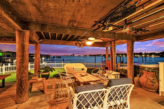 patio terrace at dusk featuring a deck with water view