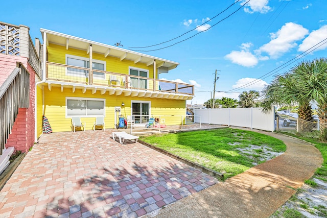 rear view of property with a yard, a balcony, and a patio