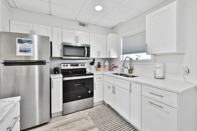 kitchen with white cabinets, appliances with stainless steel finishes, a drop ceiling, and sink