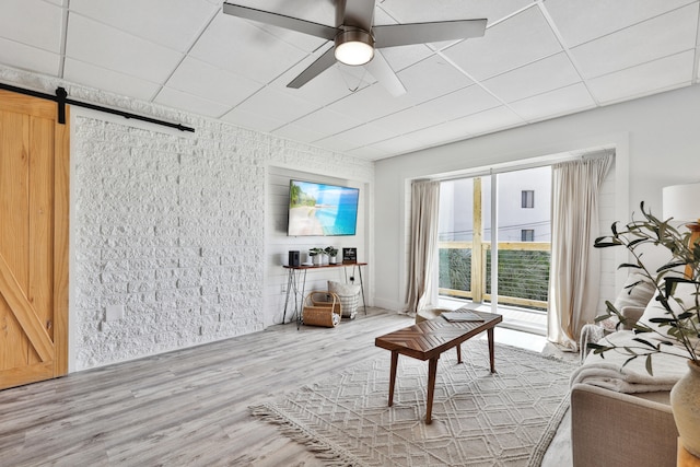 living room featuring a barn door, hardwood / wood-style flooring, and ceiling fan