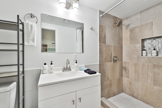 bathroom with vanity, toilet, and a tile shower