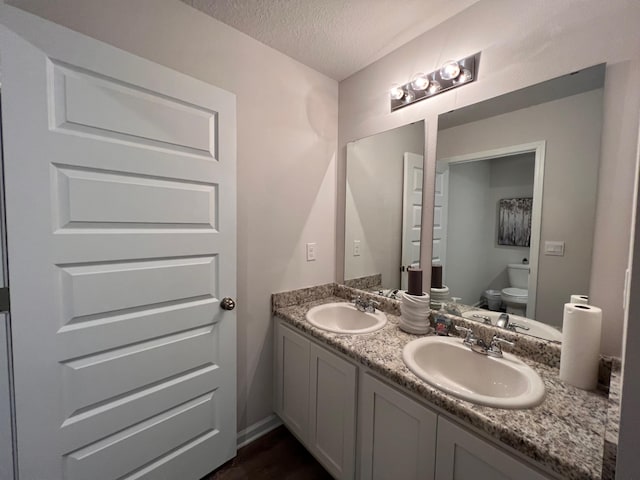 bathroom with vanity, toilet, and a textured ceiling