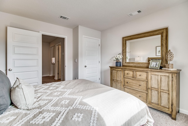 bedroom with a textured ceiling and light colored carpet