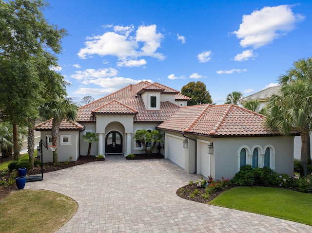 mediterranean / spanish home featuring a garage and a front lawn