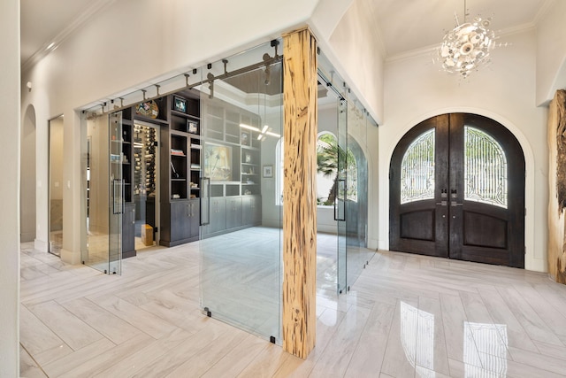 entryway with french doors, a towering ceiling, parquet floors, and a chandelier