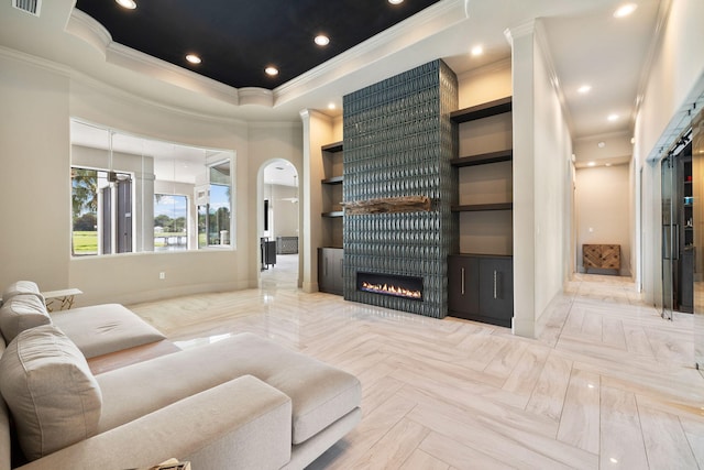 living room featuring crown molding, light parquet flooring, a fireplace, and a raised ceiling