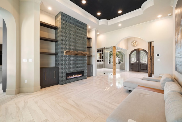 living room featuring french doors, a large fireplace, ornamental molding, and a high ceiling