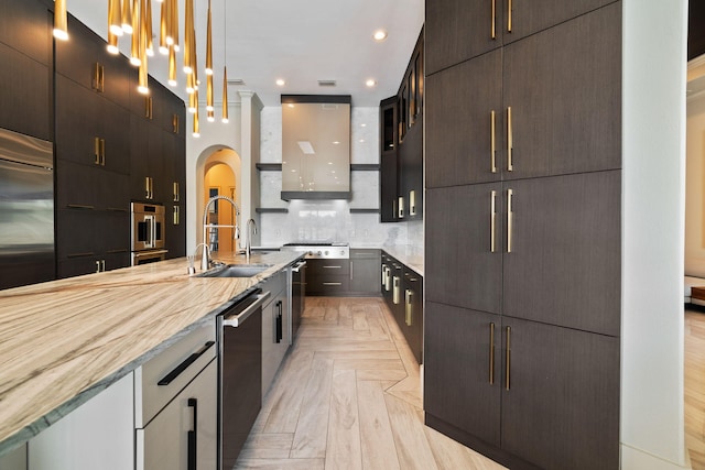 kitchen featuring sink, backsplash, hanging light fixtures, light parquet floors, and wall chimney range hood