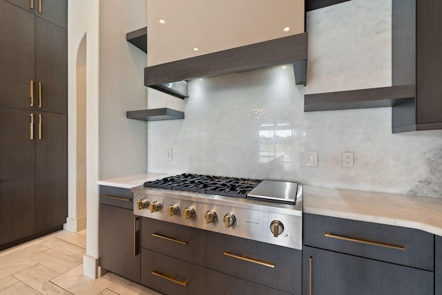 kitchen with stainless steel gas stovetop, light tile patterned floors, custom range hood, and backsplash