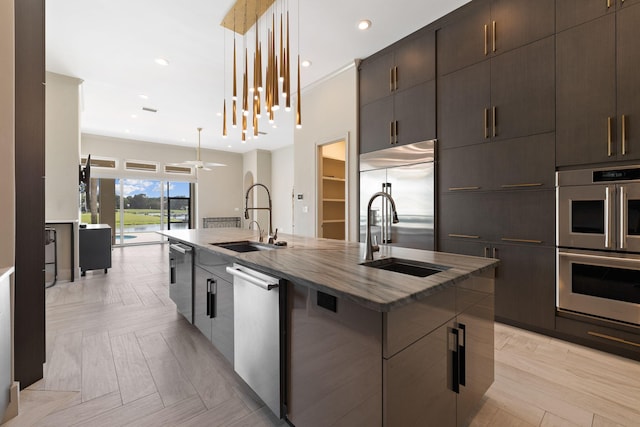 kitchen featuring pendant lighting, appliances with stainless steel finishes, sink, and a center island with sink