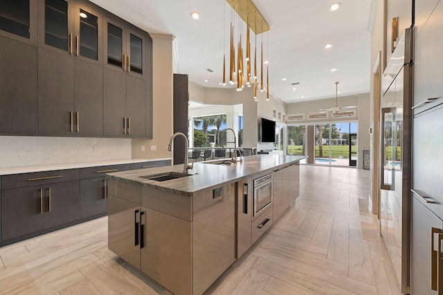 kitchen featuring hanging light fixtures, an island with sink, light parquet floors, and sink