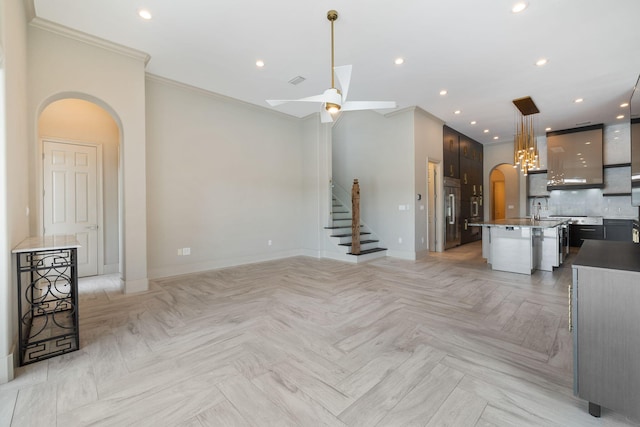 unfurnished living room featuring crown molding, ceiling fan, sink, and light parquet floors